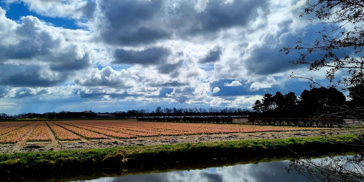 Akker met sloot onder een wolkenlucht